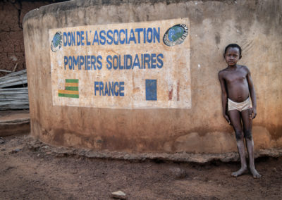 Petit garçon togolais devant des latrines construites par pompiers solidaires dans son village de Notse